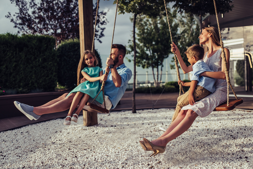 Eine Familie schaukelt gemeinsam auf einer Schaukel. Vater, Mutter und Kinder verbringen zusammen Zeit.