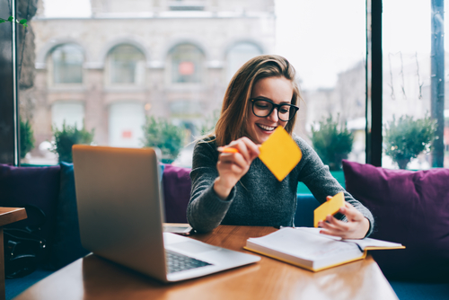 Frau sitzt am Laptop, macht Notizen und freut sich - Webdesign für Seo und Barrierefreiheit