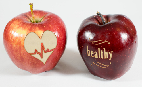 2 rote Äpfel eines mit Herz mit Heartbeat-Symbol und das Wort healthy eingeritzt