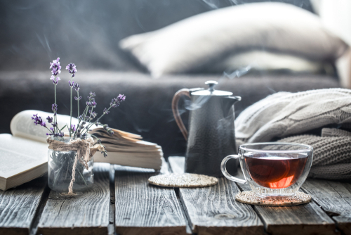 Stillleben von einem Wohnzimmer, im Vordergrund steht ein Tee, Lavendel und ein Buch