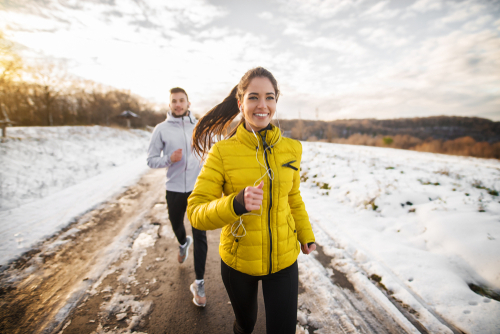 Frau und Mann, die im Winter im Schnee joggen und trainieren