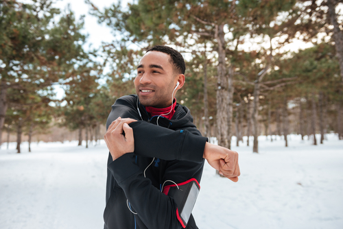 Mann dehnt sich im Schnee im Wald. Outdoortraining im Winter.