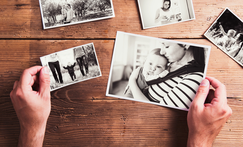 Männerhände halten schwarzweiß Fotos. Bilder von der Familie.