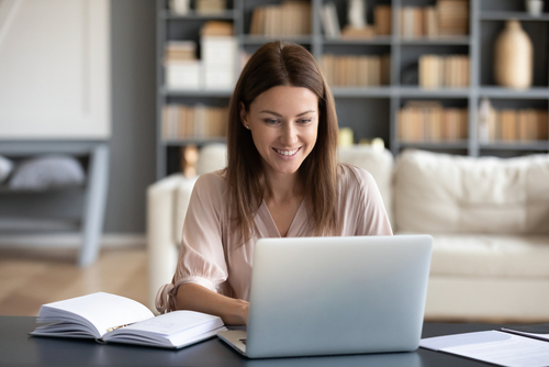 Frau sitzt vor Laptop mit Notizbuch, Website erstellen, Sichtbarkeits Coaching