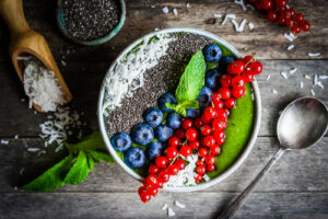 Grüner Smoothie Schüssel mit Beeren auf Holzhintergrund